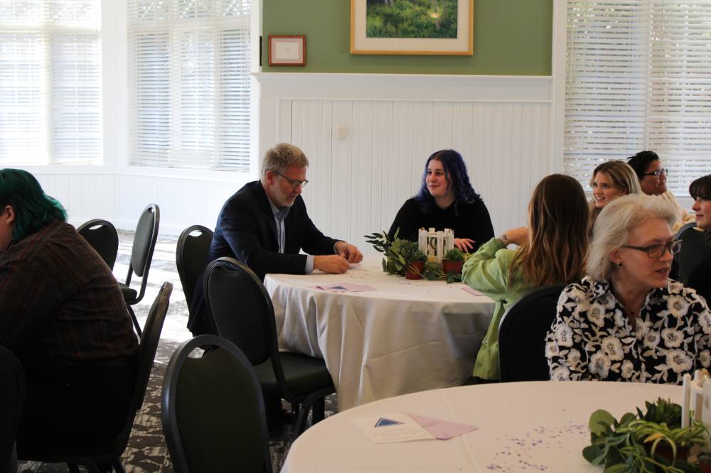 Dean of Brooks College Mark Schaub at a table having a conversation with fellow event attendees